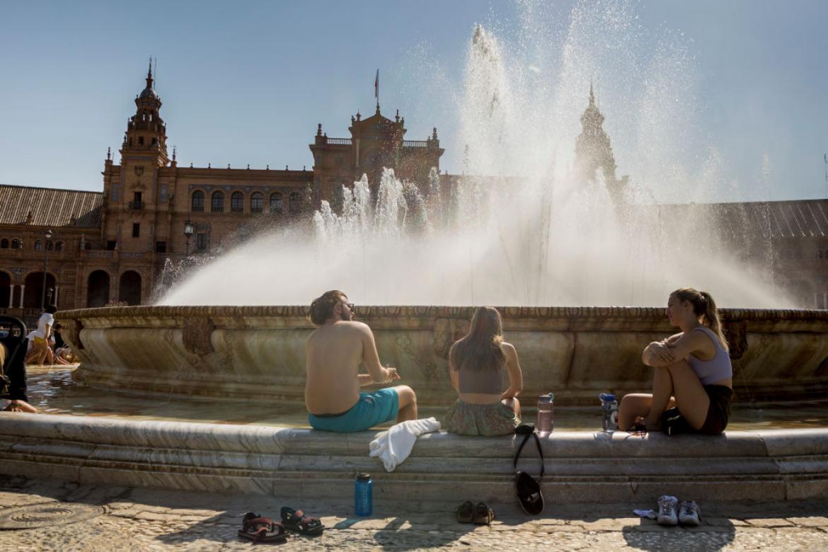 Tres turistas se refrescan en la fuente de la Plaza de España, en Sevilla.