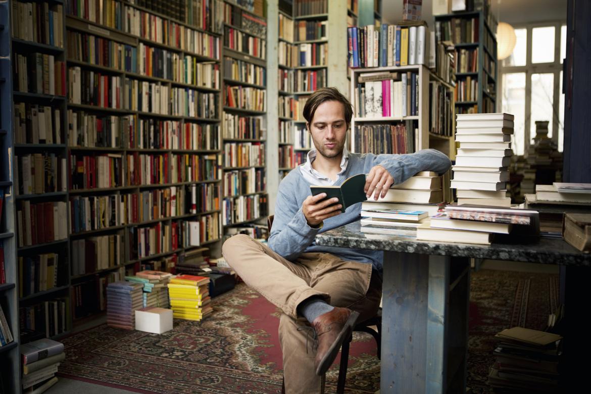 Un hombre leyendo en una biblioteca repleta de libros