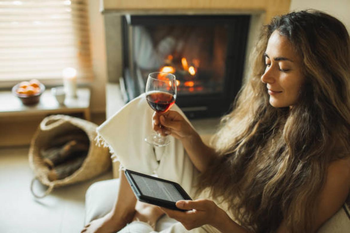 Leisure and relaxation in evening. Beautiful lady with long hair sitting on sofa at fireside and reading electronic book. Cozy home. Hobby and pleasure. Cute girl resting.