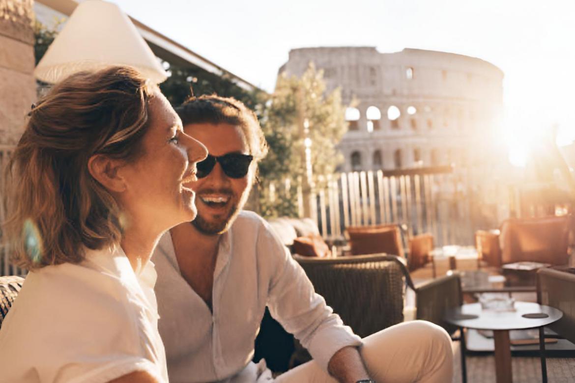 Una pareja riéndose al atardecer con el Coliseo de fondo en Roma