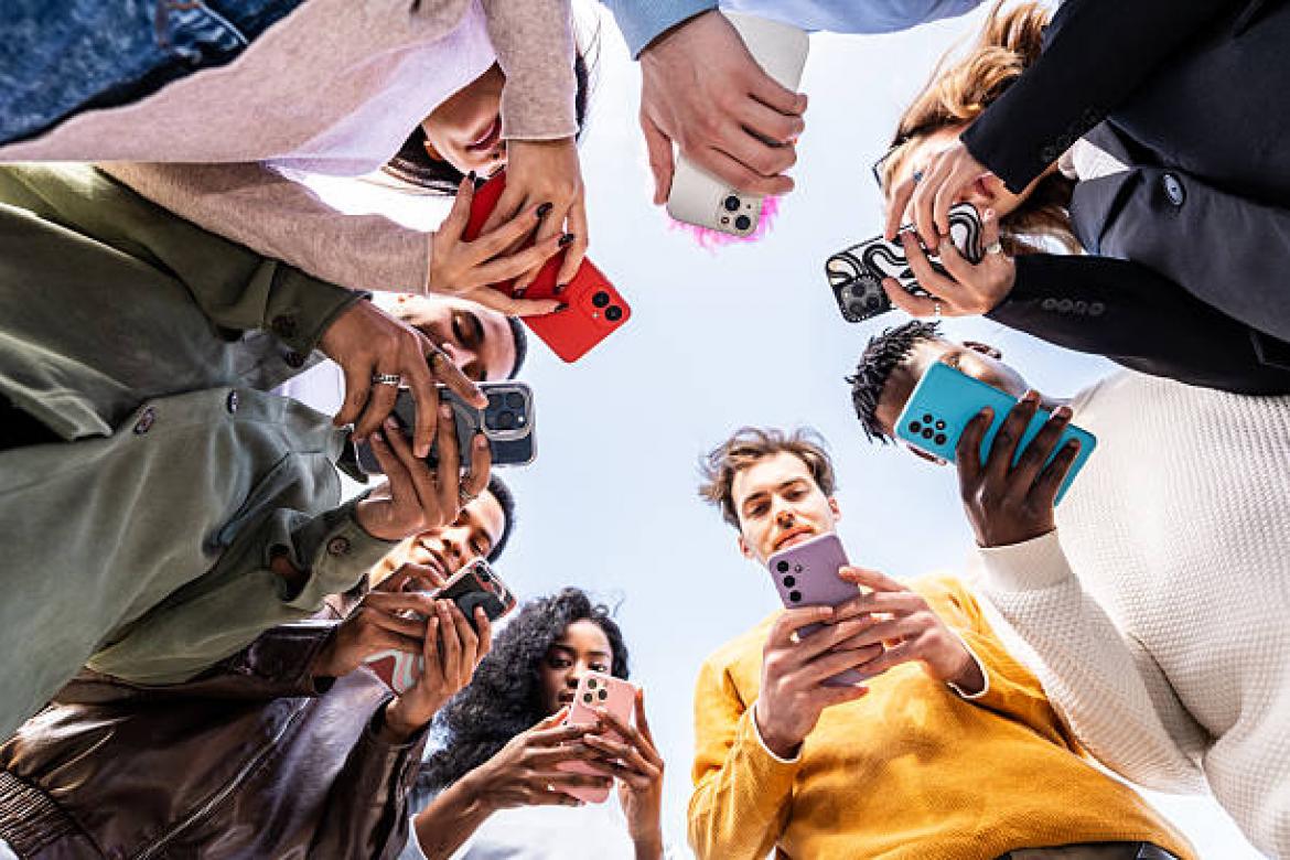 Group of young people using smartphones, forming a circle and looking down at their phones