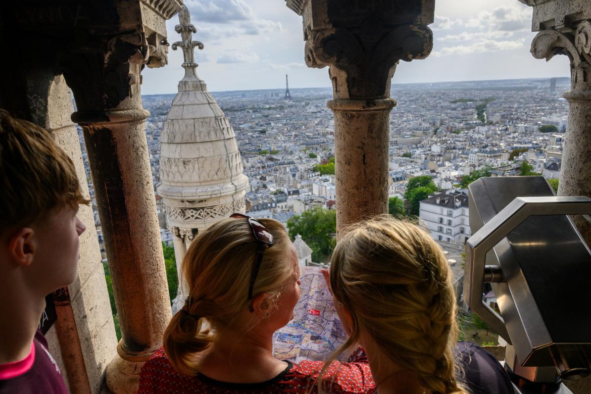 Turistas en la torre de la Basílica del Sagrado Corazón de París, con la Torre Eiffel al fondo.