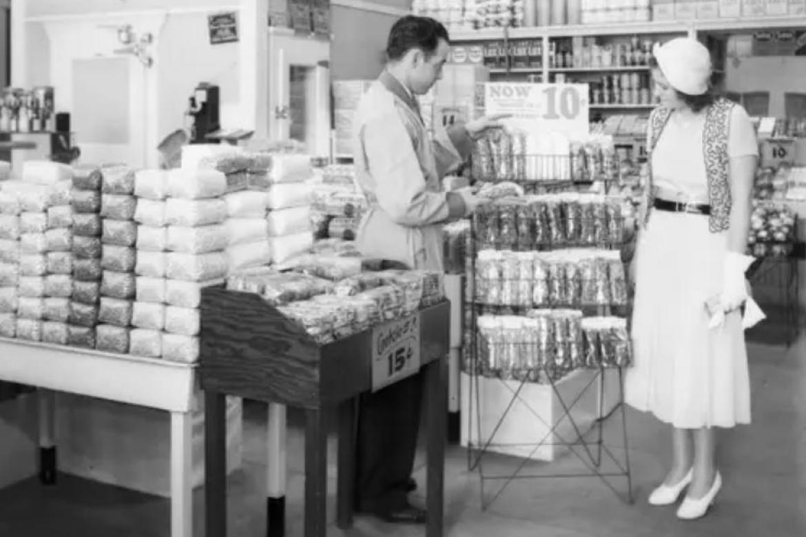 Un empleado ayuda a una mujer en un supermercado de 1930