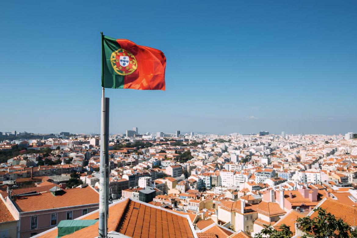 La bandera de Portugal ondeando con el skyline de Lisboa de fondo