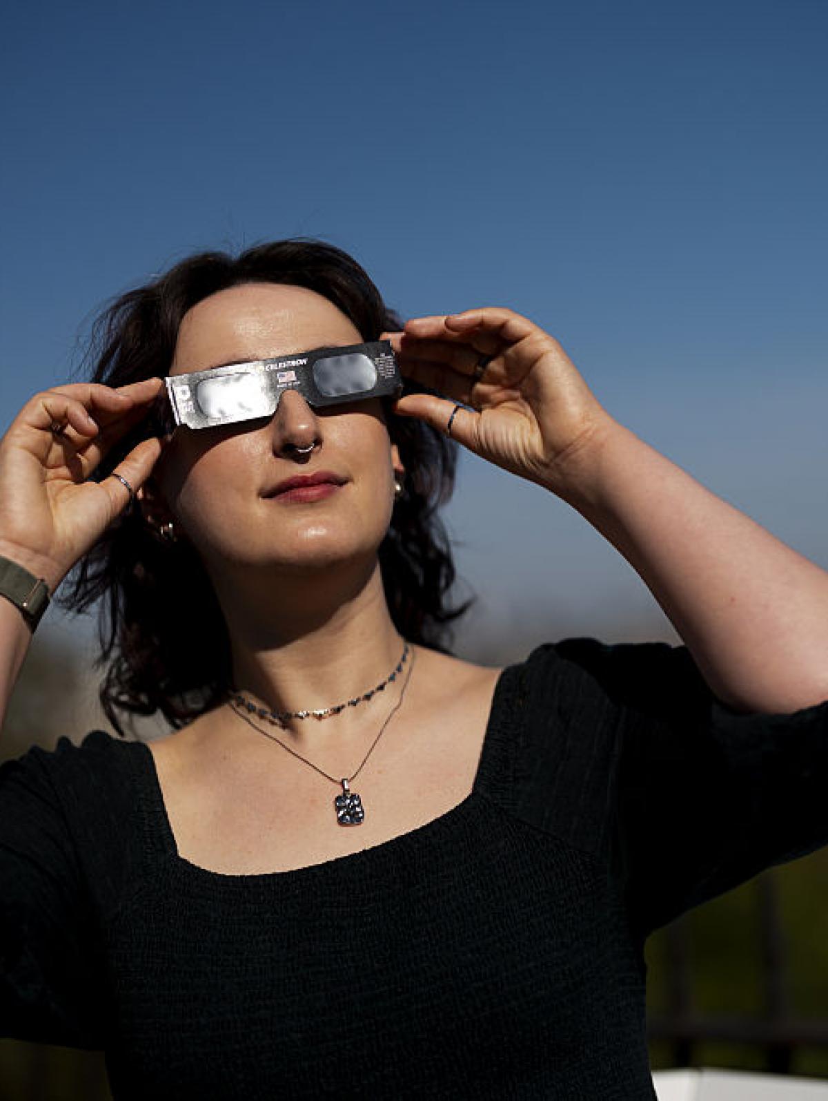 Una astrónoma mira al cielo con sus gafas del eclipse