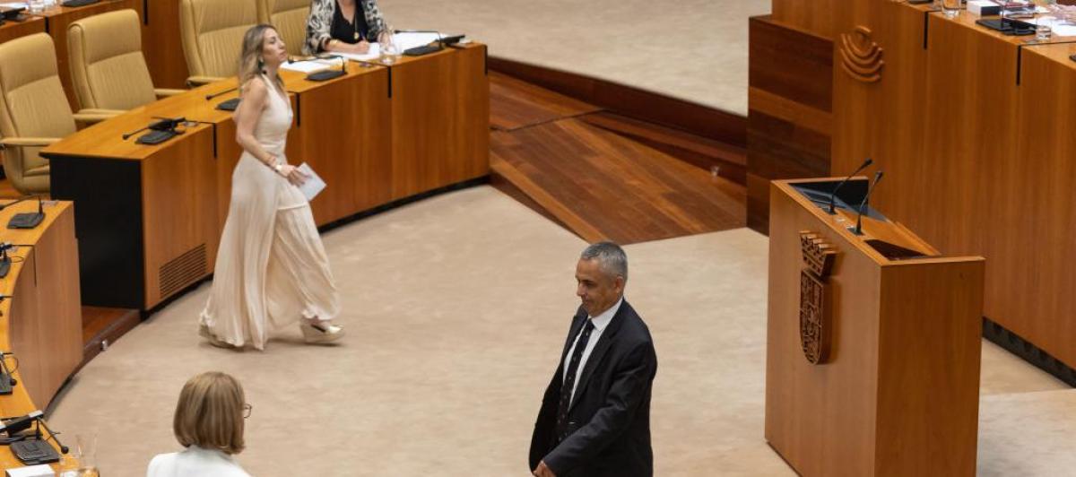 La candidata popular, María Guardiola, se aproxima a la mesa de la Asamblea mientras Ángel Pelayo, candidato de Vox, se aleja de la misma.