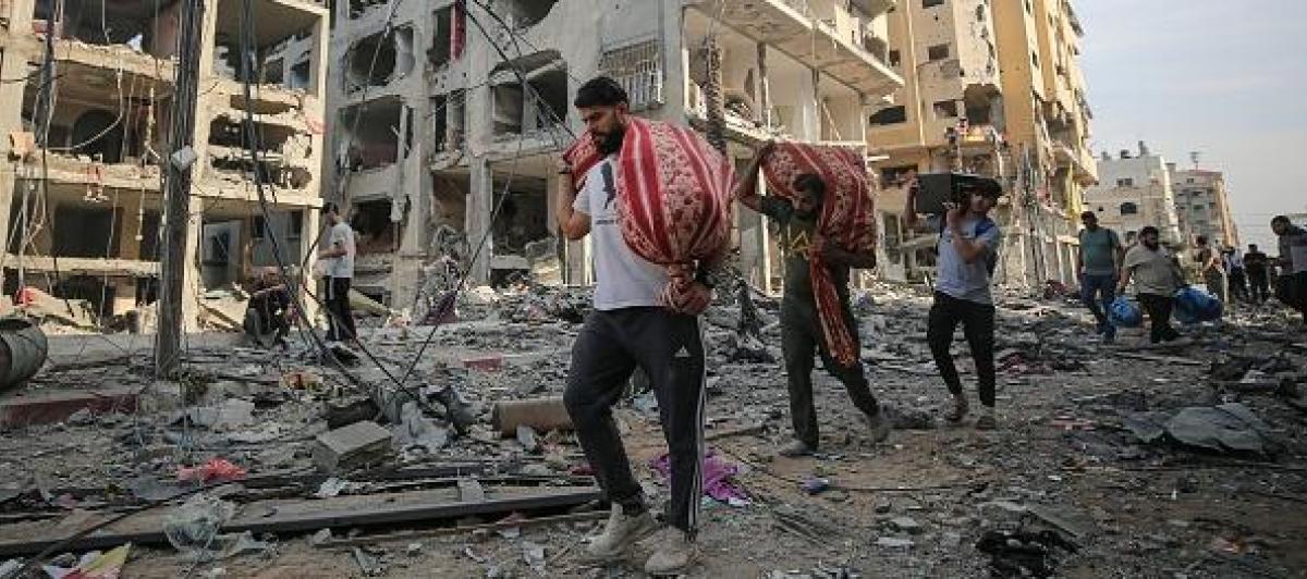 Ciudadanos gazatíes abandonan sus hogares devastados tras los bombardeos israelíes en respuesta al ataque de Hamás, con las pocas pertenencias que pueden cargar.