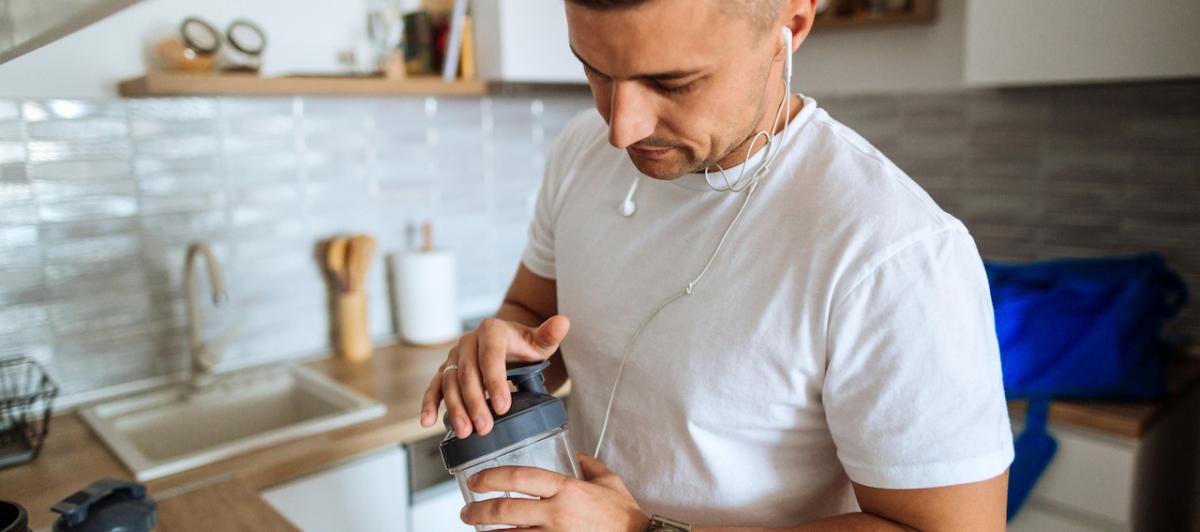 Un hombre se prepara un batido proteínico antes de entrenar.