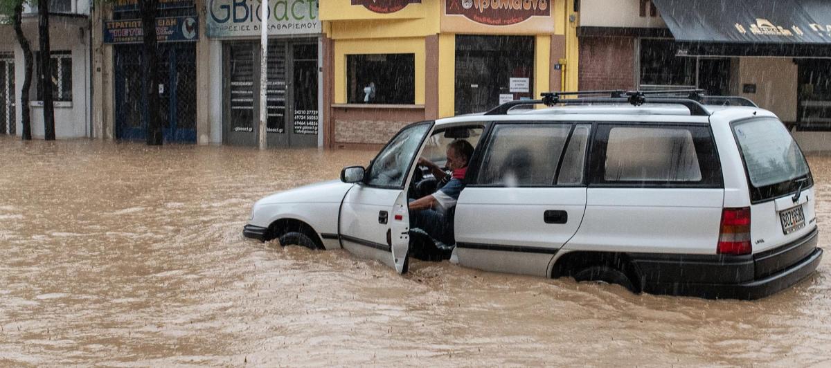 Un hombre trata de salir de su vehículo al verse sorprendido por la riada en la capital de la región griega de Magnesia, Volos.