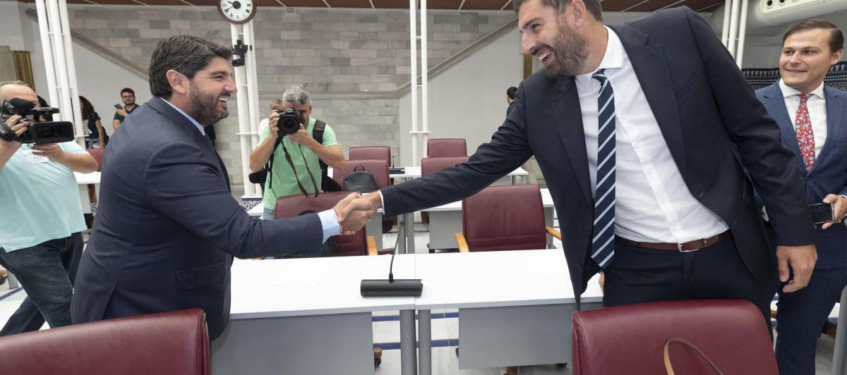 El presidente reelecto de Murcia, Fernando López Miras, saluda al portavoz de Vox en el parlamento murciano, José Ángel Antelo, a su llegada a la segunda sesión del pleno de investidura.
