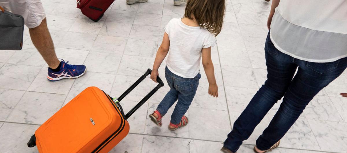 Una niña arrastra su maleta de mano por un aeropuerto en Europa.