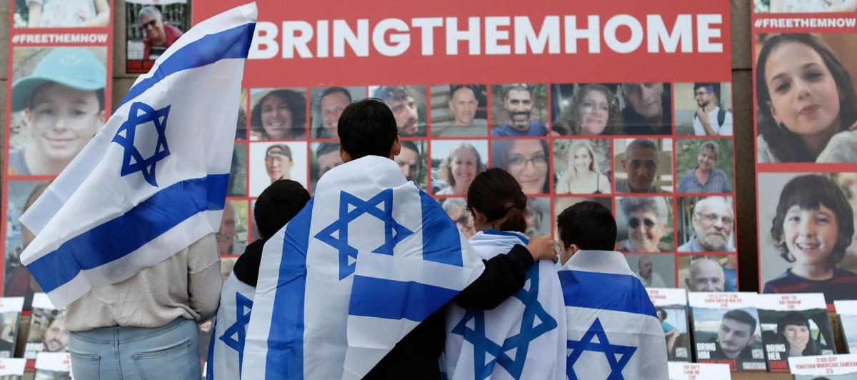 Niños envueltos con la bandera israelí miran los retratos de los civiles secuestrados por Hamás, durante una manifestación en favor de Israel celebrada en la Biblioteca Universitaria Central de Bucarest, el 2 de noviembre.