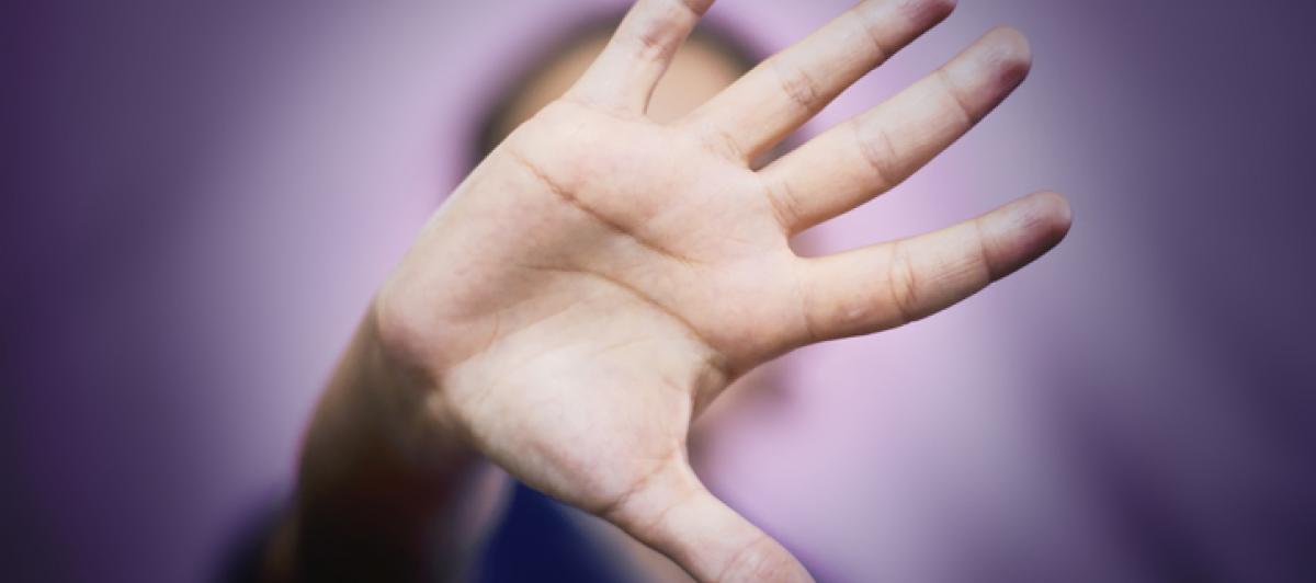Imagen de una mujer con la mano ocultando su rostro, en gesto de basta ya.