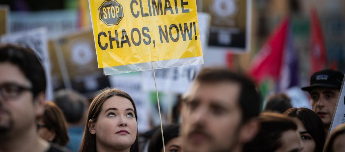 Un joven con una pancarta que pide parar el "caos climático, ya".