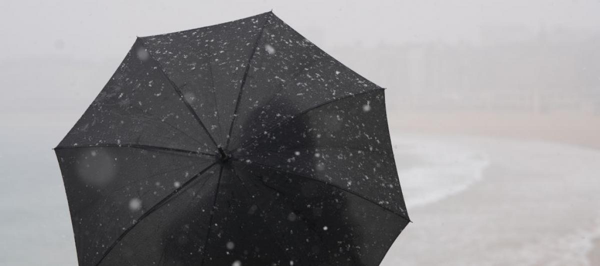 Una persona se protege del frío y el viento con un paraguas