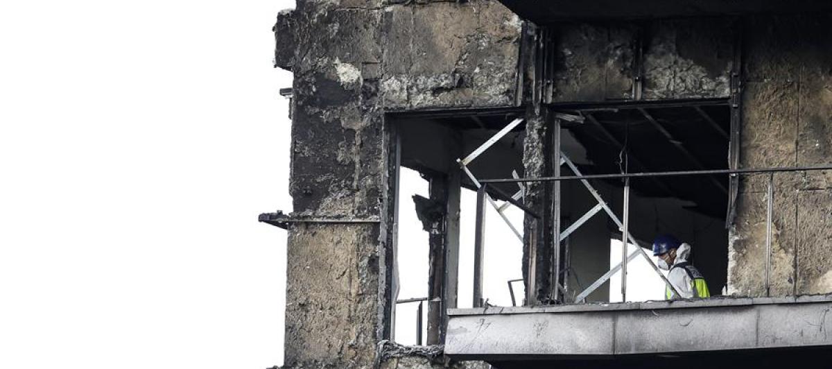 Un agente de la Policía Científica inspecciona una vivienda del edificio incendiado en el barrio de Campanar de Valencia