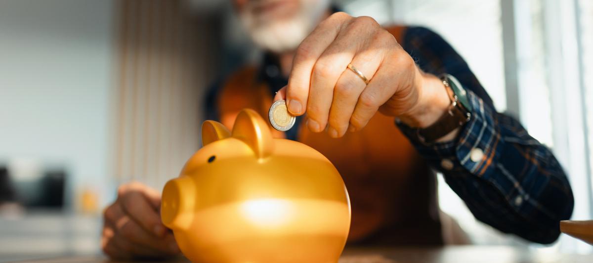 Un hombre echando dinero en una hucha