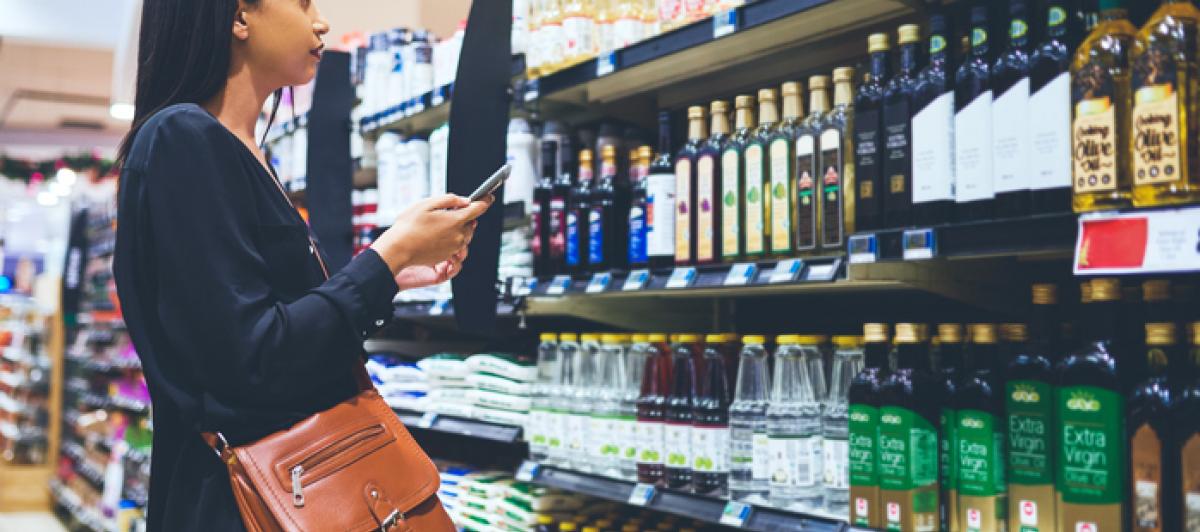Imagen de una mujer comprobando varias marcas de aceite de oliva en un supermercado.