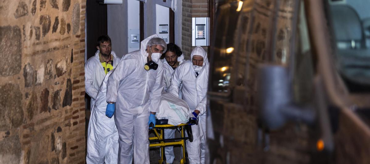 Miembros de los servicios funerarios trasportan uno de los cuatro cadáveres encontrados hoy martes en la calle Santa Leocadia de Toledo, localizados en una vivienda de la capital.