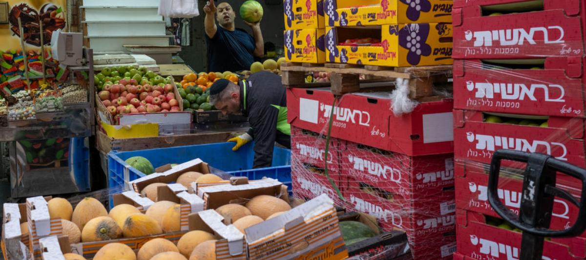Trabajadores del mercado de Mahane Yehuda, Jerusalén, reponen productos en su puesto.