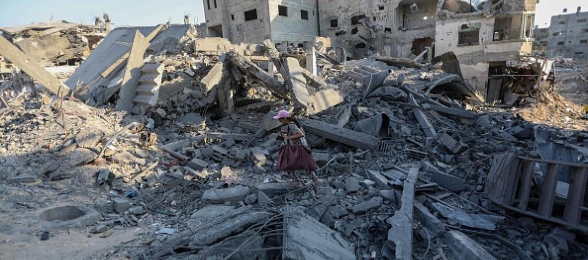 Imagen de archivo de una niña caminando con escasas pertenencias entre los restos de edificios bombardeados por el Ejército de Israel, en la Franja de Gaza.