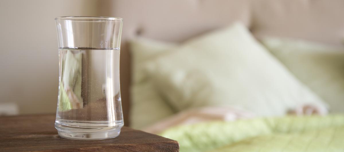 Un vaso de agua en una mesilla.