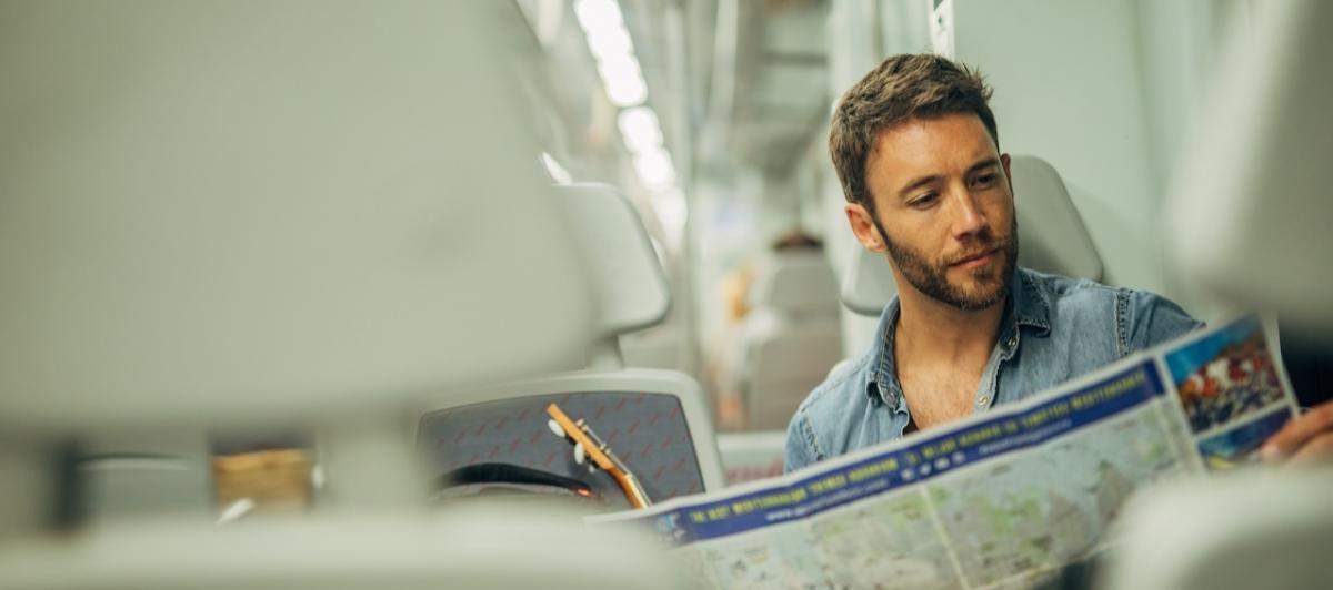 Un turista consulta un mapa de de España mientras viaja en tren.