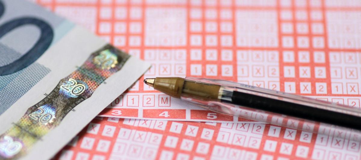 Primer plano de una quiniela, de un billete de 20 euros y un bolígrafo
