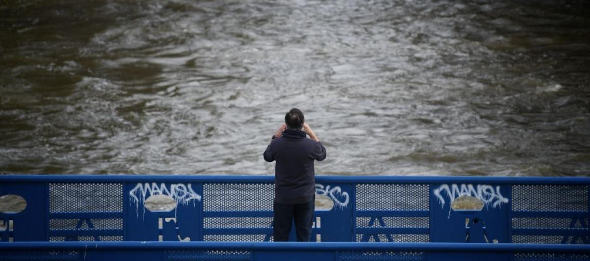 Una persona fotografía el curso del río de Manzanares, crecido por las intensas lluvia que trae la borrasca Martinho.