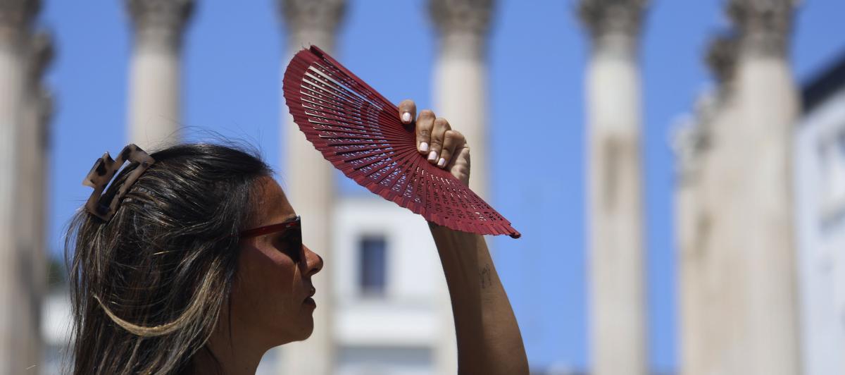 Una joven se tapa la cara con un abanico mientras camina por el centro de Córdoba, en plena ola de calor.