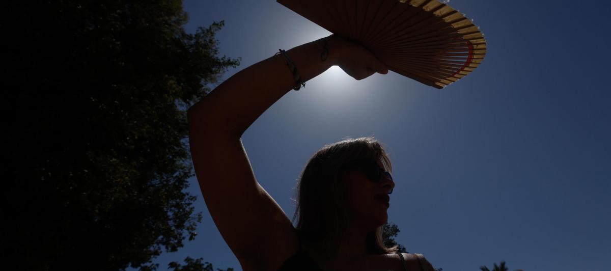 Una mujer se protege con un abanico del sol en Córdoba.