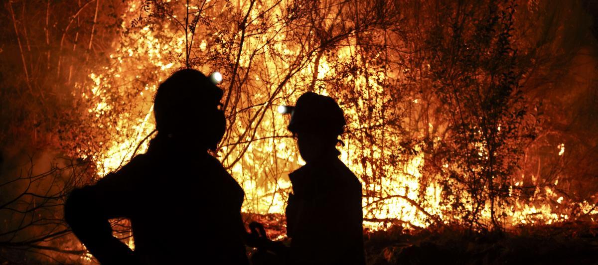 Bomberos forestales antes las grandes llamas del incendio en Aguasmestas, una parroquia del municipio de Quiroga, en la provincia de Lugo.