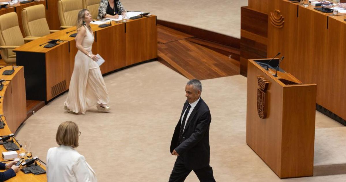 La candidata popular, María Guardiola, se aproxima a la mesa de la Asamblea mientras Ángel Pelayo, candidato de Vox, se aleja de la misma.