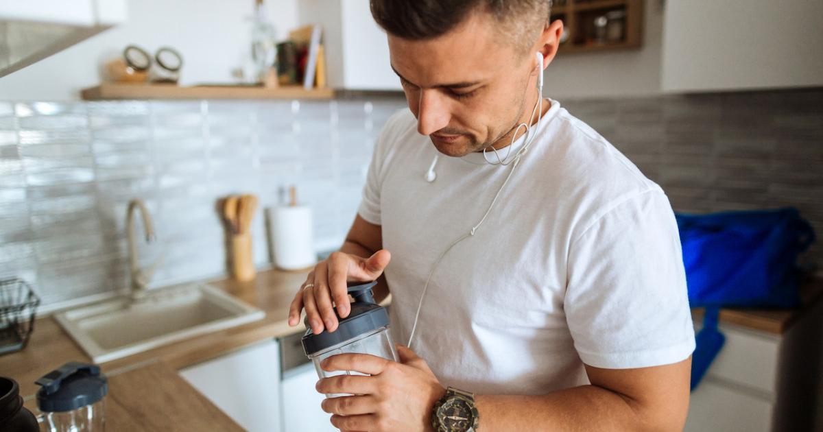 Un hombre se prepara un batido proteínico antes de entrenar.