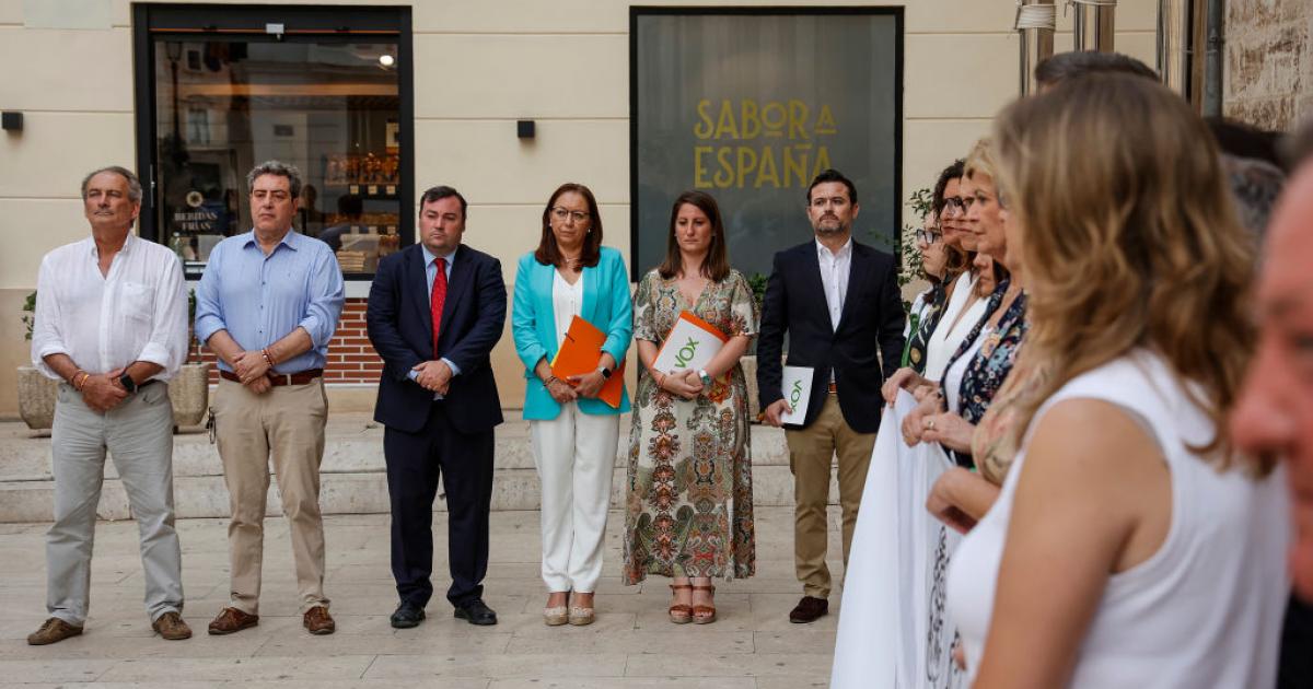 Representantes de Vox, al fondo, separados de la pancarta que denuncia el crimen machista de Antella, en primer término.