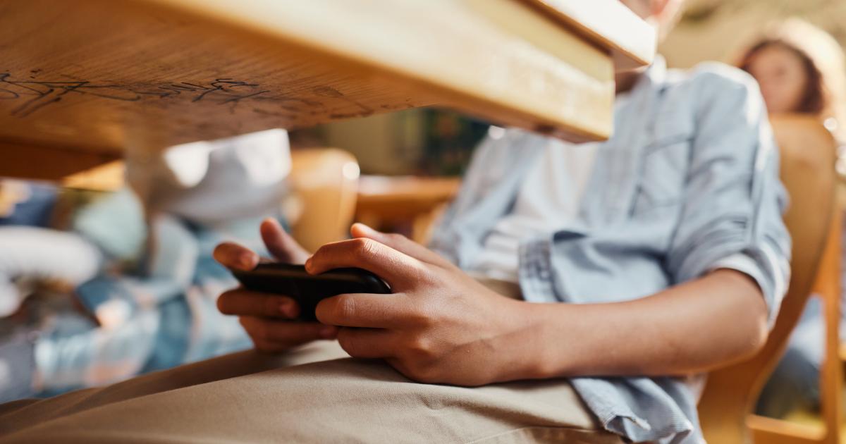 Imagen de archivo de un alumno usando su teléfono móvil en clase.