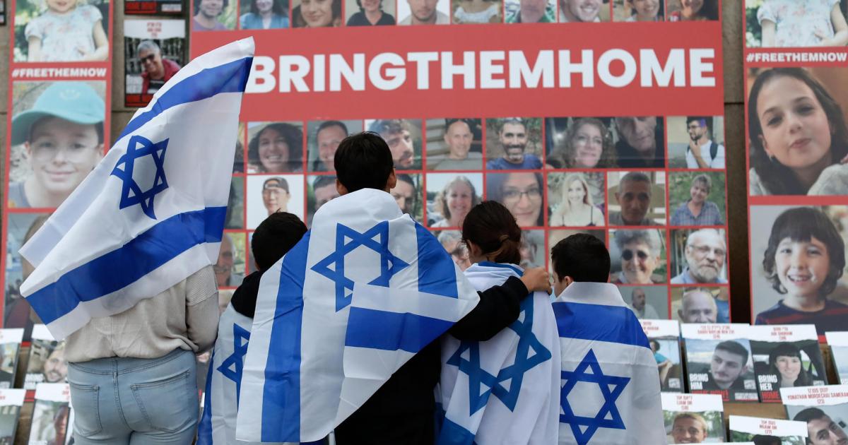 Niños envueltos con la bandera israelí miran los retratos de los civiles secuestrados por Hamás, durante una manifestación en favor de Israel celebrada en la Biblioteca Universitaria Central de Bucarest, el 2 de noviembre.