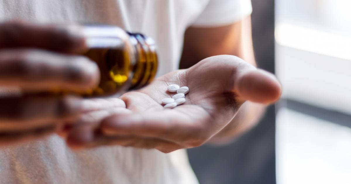 Imagen de archivo de una mujer tomando varias píldoras de un bote.