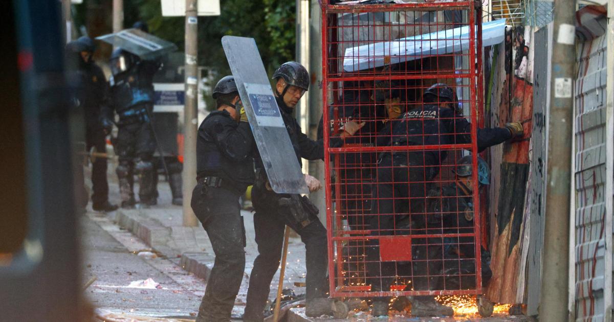 Los ocupas han lanzado sacos de escombros, botes de humo y bengalas para dificultar la intervención policial, en la que los Mossos han recurrido a una jaula metálica protectora para acceder.