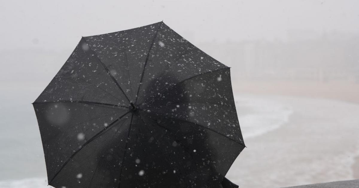 Una persona se protege del frío y el viento con un paraguas