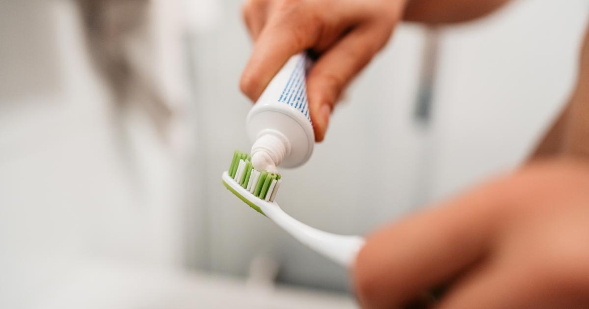 Una persona poniendo pasta a su cepillo de dientes.
