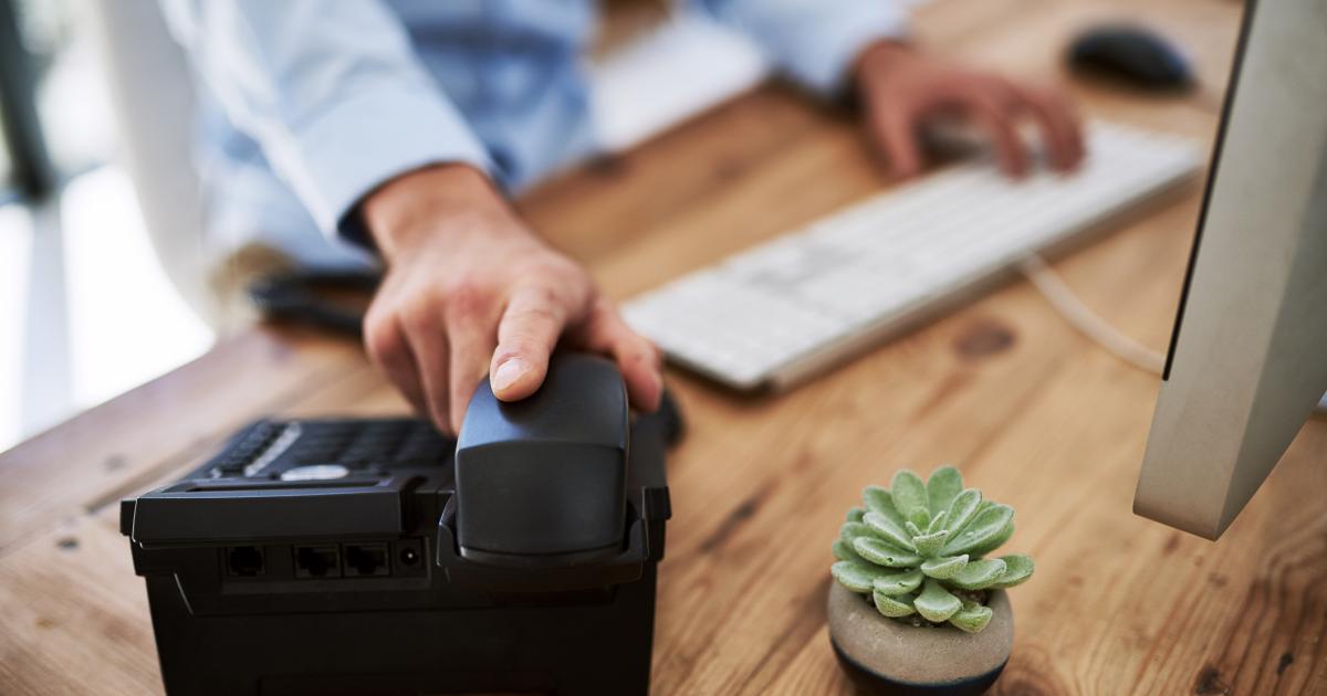 Una persona cogiendo el teléfono en el trabajo.