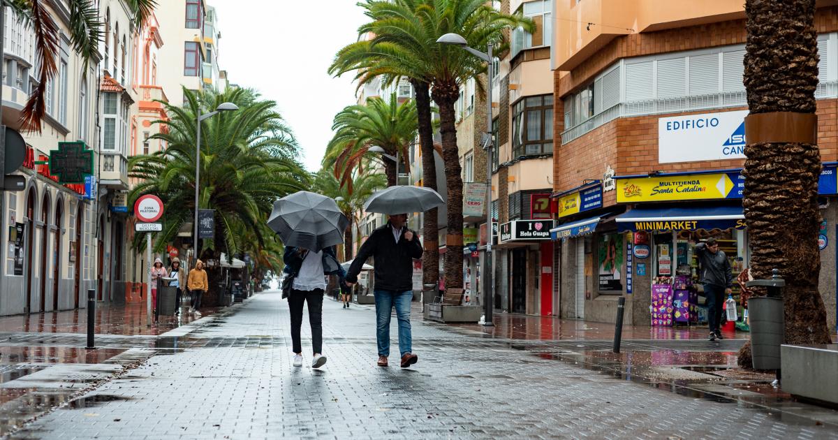 Dos personas con un paraguas, resguardándose de la lluvias en Las Palmas de Gran Canaria.