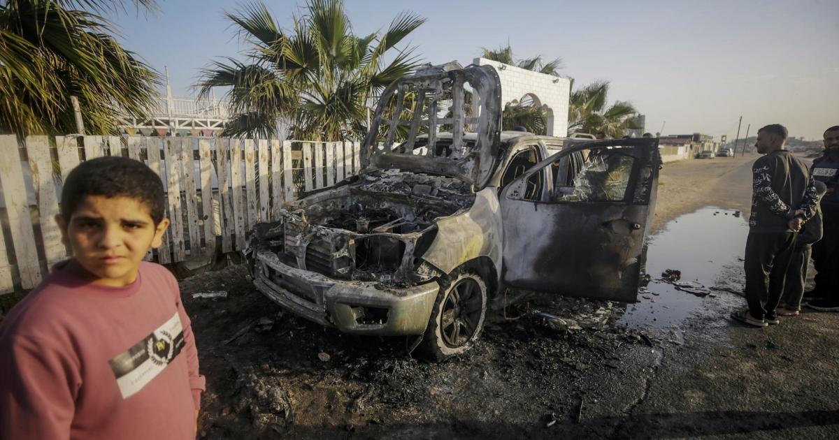 Varias personas observan la destrucción de uno de los vehículos del convoy de ayuda humanitario de la oenegé World Central Kitchen (WCK).