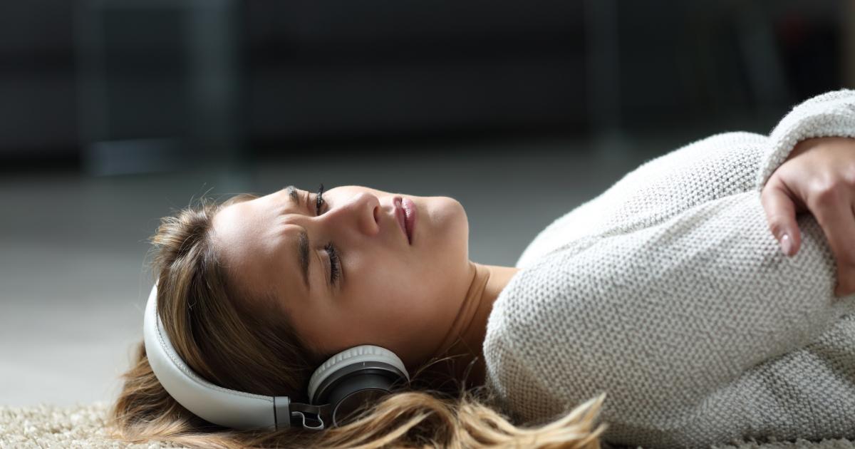Una joven escuchando música con apariencia triste.