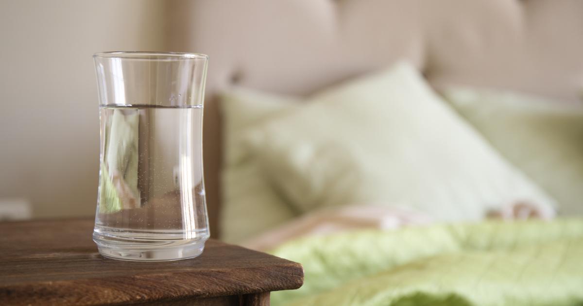 Un vaso de agua en una mesilla.