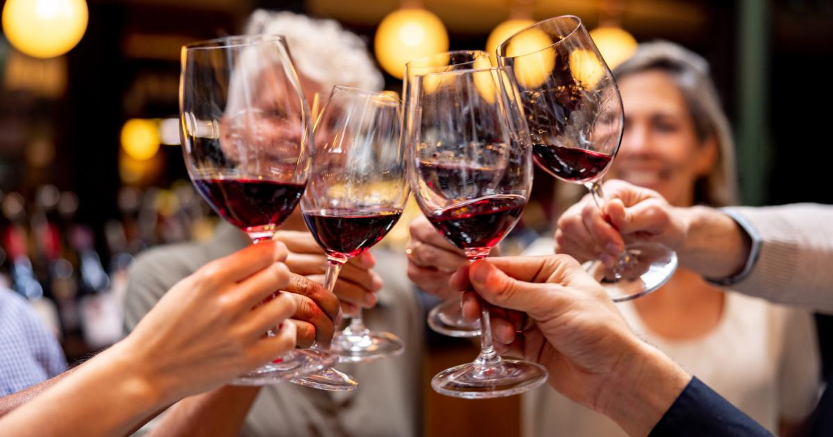 Un grupo de adultos brinda con vino.