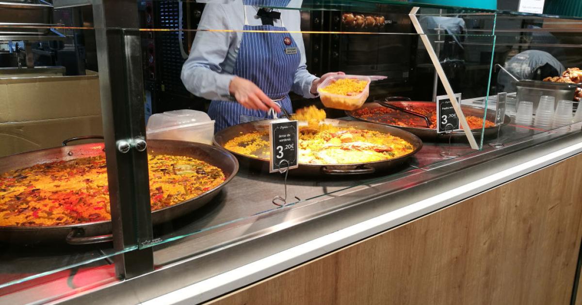 Una trabajadora de un supermercado prepara una ración de un plato preparado