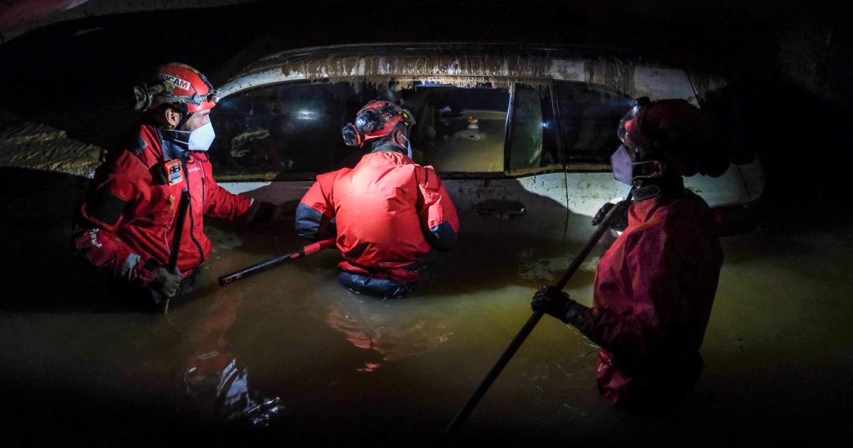 Bomberos inspeccionan un vehículo con el agua por la cintura