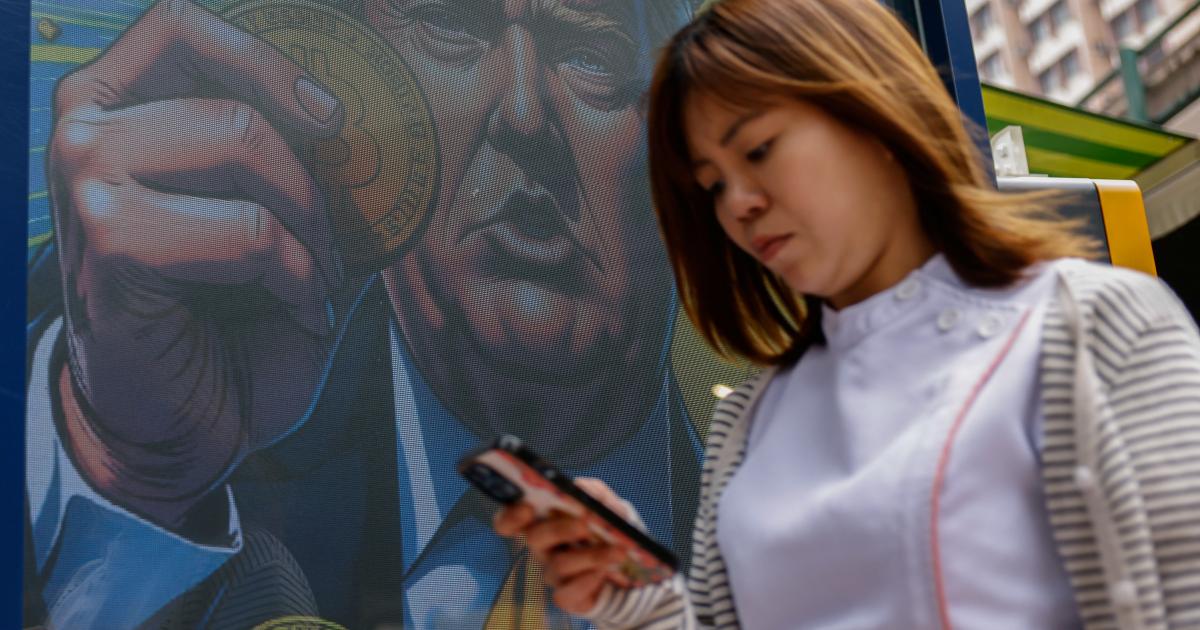 Una persona pasea junto a una ilustración del presidente reelecto Donald Trump, en Hong Kong.